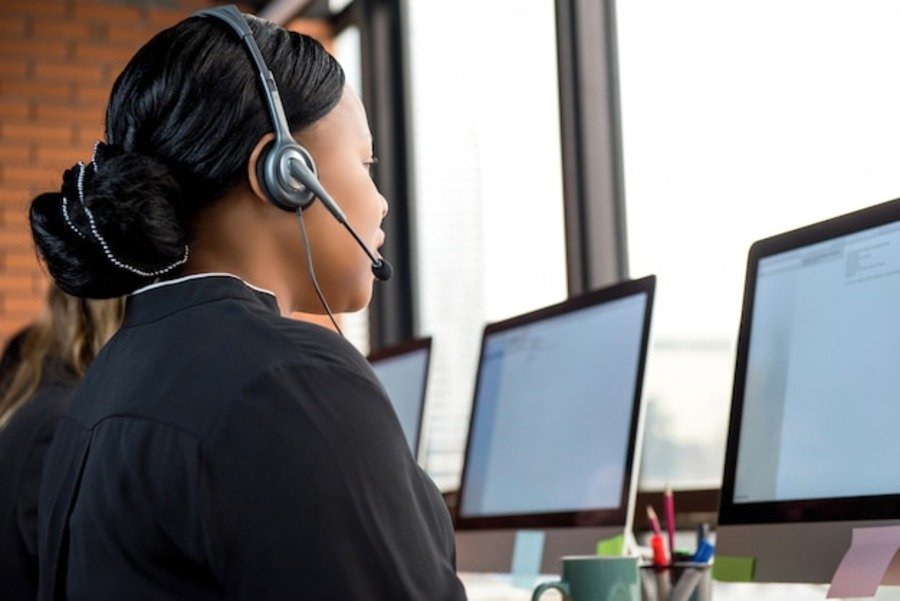 Businesswoman wearing a headset working at a call center, focusing on IT support services in a modern office environment.